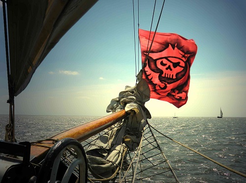 Mast eines Segelschiffes mit Piratenflagge auf dem Meer in Holland
